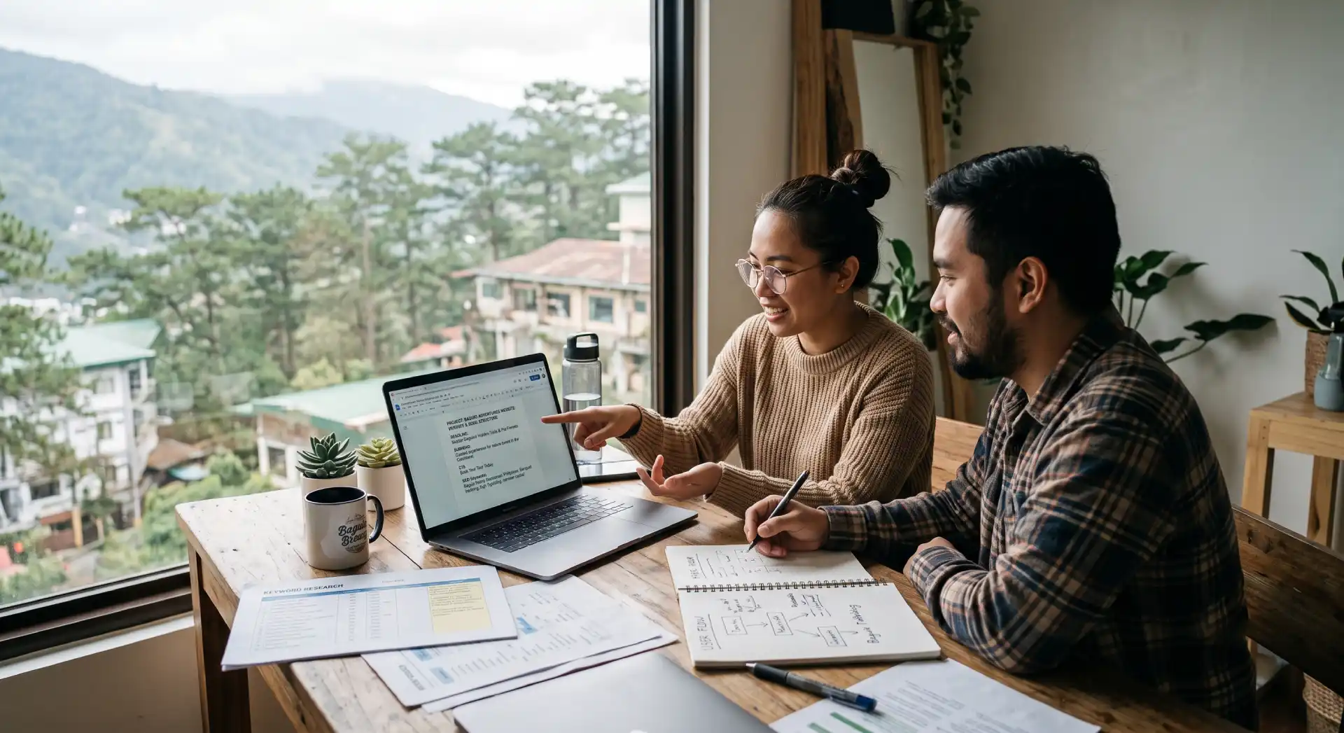 Two professionals collaborating on website copywriting and content strategy using a laptop with notes and documents in a home office overlooking Baguio