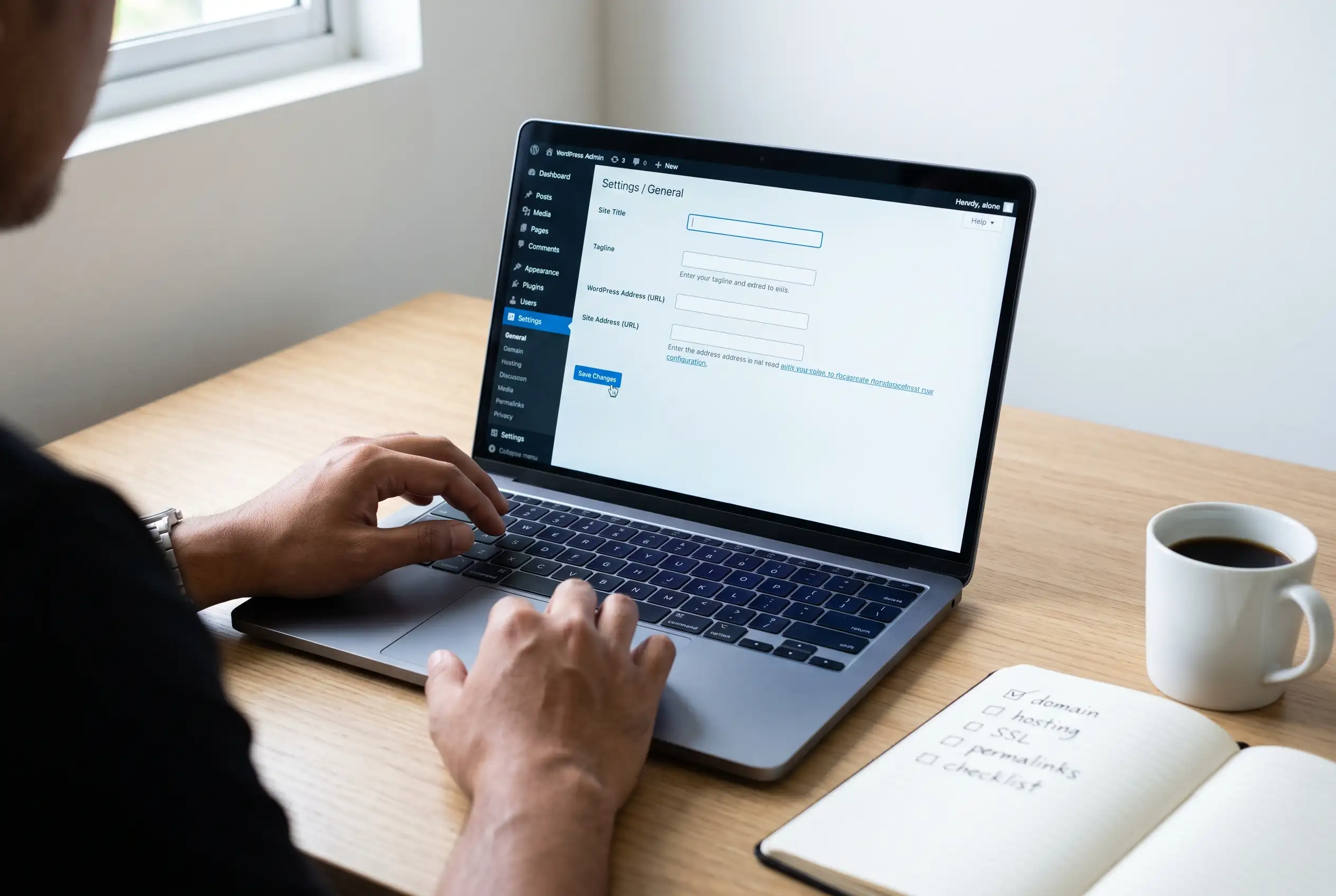 WordPress admin dashboard settings panel open on a laptop screen with the General Settings page visible, showing Site Title and Tagline fields ready to be filled in
