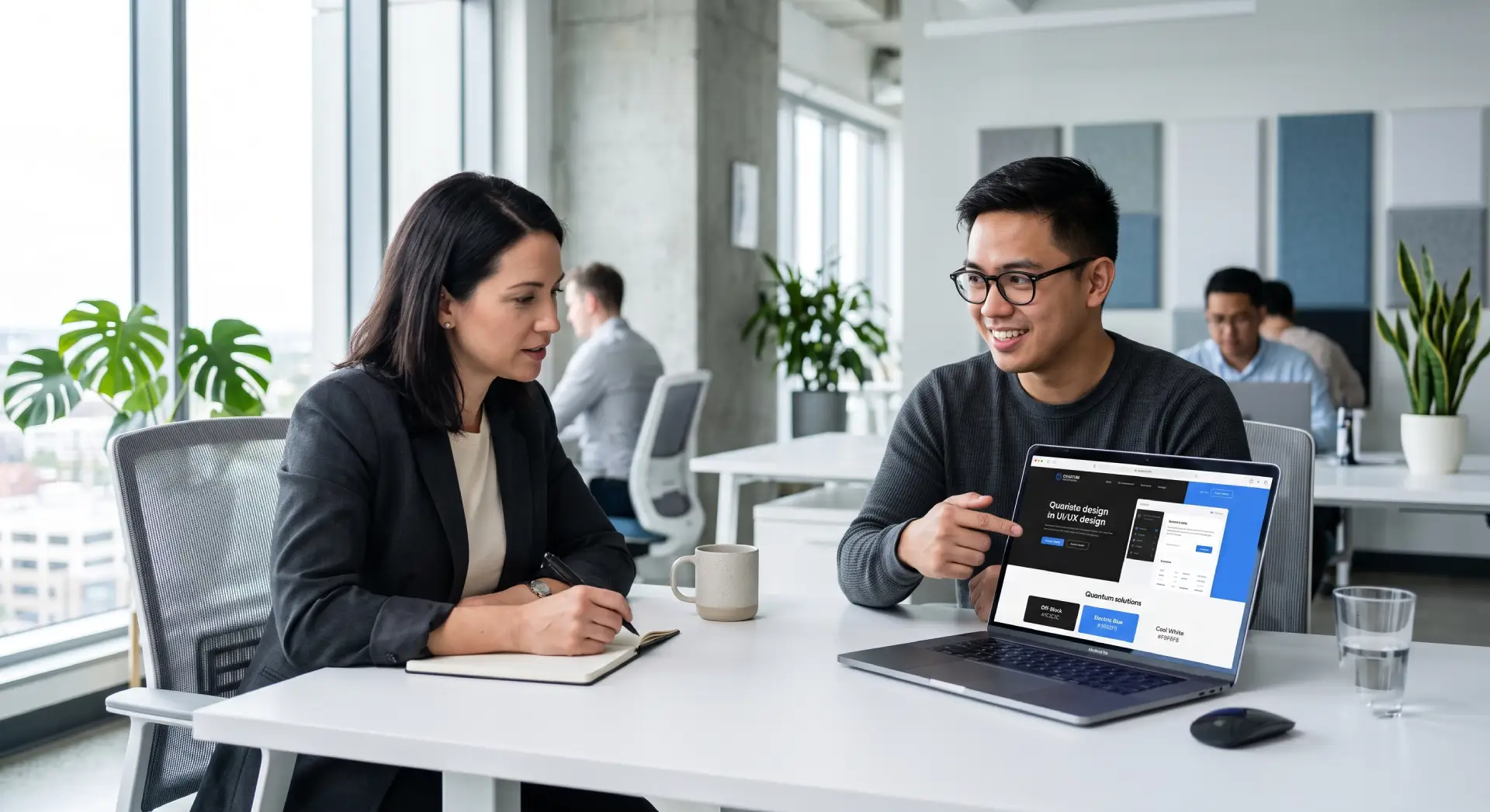 Business owner interviewing a web designer, both reviewing a website mockup on a laptop screen